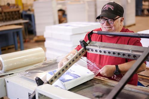 Jeff Lang works on shrink-wrapping a  pack of paper.